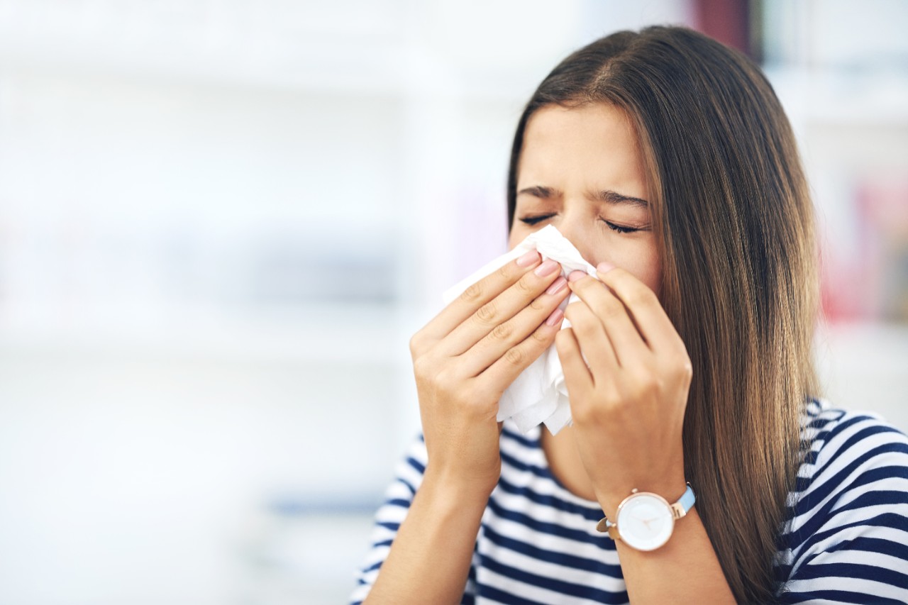 woman sneezing into tissue