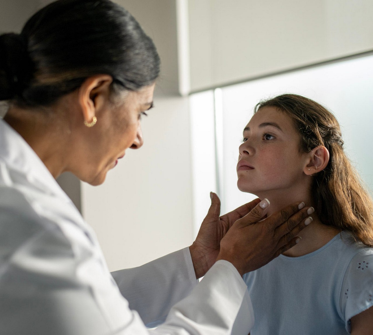 Una professionista sanitaria che valuta il collo di una paziente adolescente.