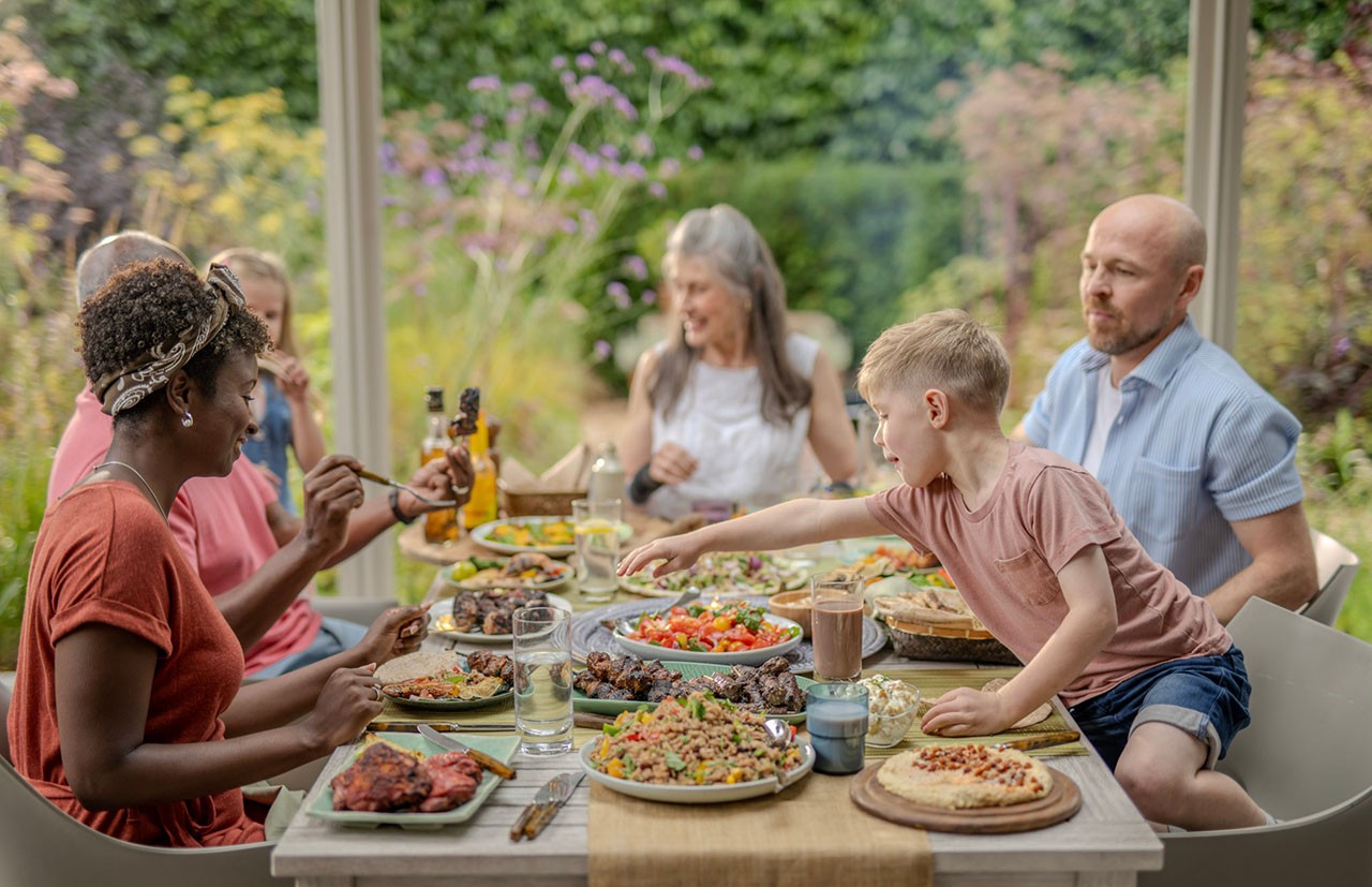 Un gruppo di amici e familiari che si godono un pasto sontuoso all'aperto sul patio