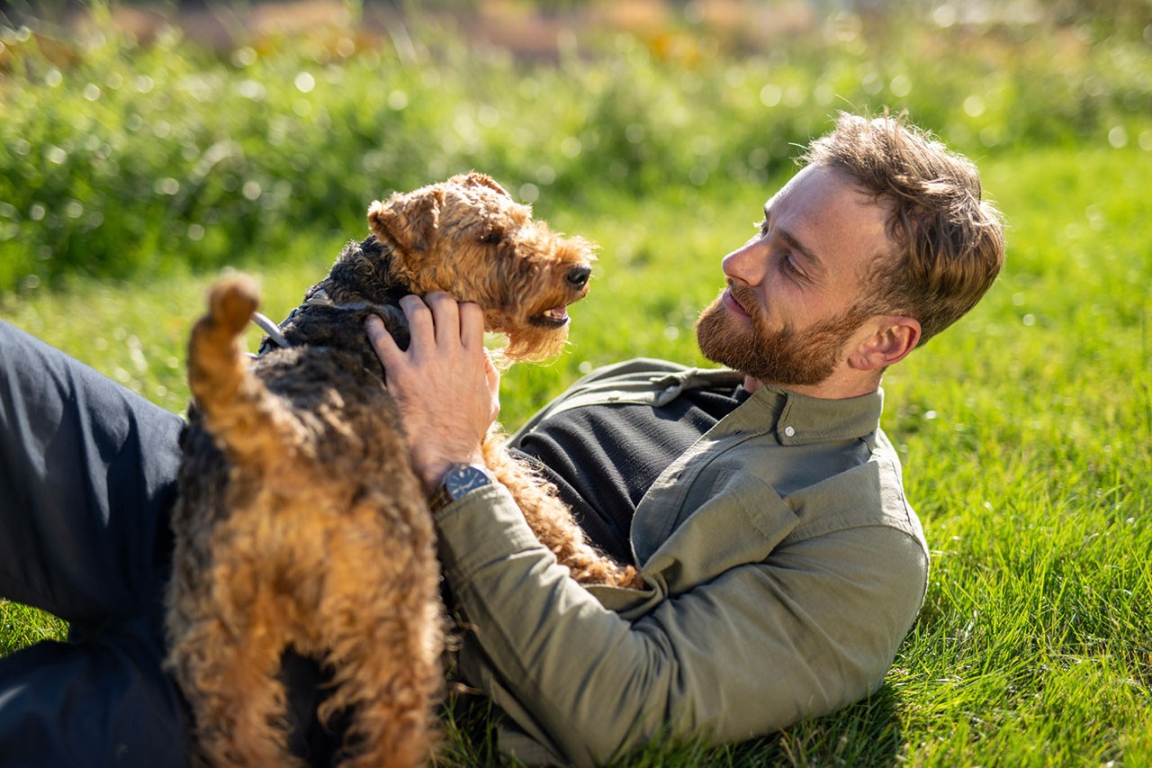 Un uomo che accarezza il suo cane mentre si rilassa fuori sull'erba