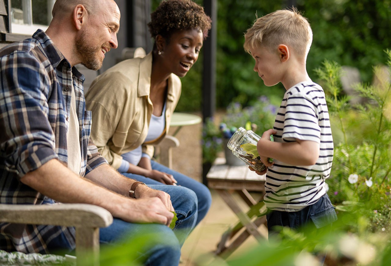 A man, woman and young boy talking outside on patio
