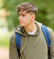 A Caucasian teenager boy in a green hoodie and backpack.